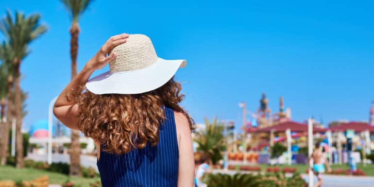 Woman in hat and blue dress go for a walk in hotel resort